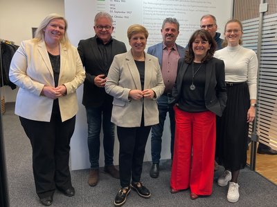 Gemeinsam stehen in der Gruppe: Bundestagsabgeordnete Maria-Lena Weiss MdB, Landtagsabgeordneter Guido Wolf MdL, Ministerin Nicole Razavi MdL, Geschäftsführer Horst Riess, Geschäftsführerin Rita Hilzinger, Baudezernent Florian Steinbrenner und die Leiterin des Wohnbau-Forums Corinna Hoffmann